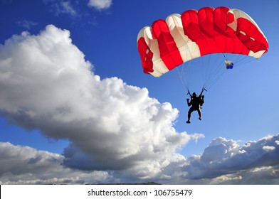 Red Parachute Landing On Stormy Sky.