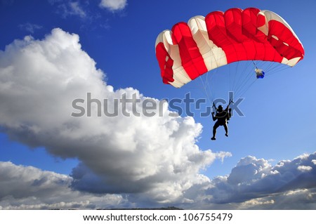 Red parachute landing on stormy sky.