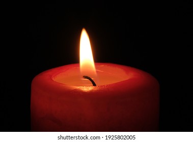 Red paraffin mournful commemorative thick candle burns on a black background close-up - Powered by Shutterstock