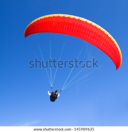 red paraglider on the blue sky