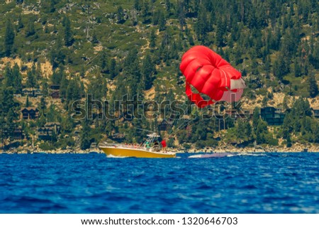 Red parasail wing pulled by a boat on lake Tahoe, summer recreation in California, USA