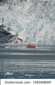 Red Passenger Cruise Ship Sailing Through The Icy Waters Of Qasigiannguit, Greenland With Eqip Sermia Eqi Glacier In Background. Ice Breaking Off From Calving Glacier. A Small Boat Among Icebergs