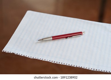 Red Pen On White Paper With Wooden Desk Background