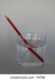 Red Pencil In A Glass Of Water, Depicting Refraction, Illusion.