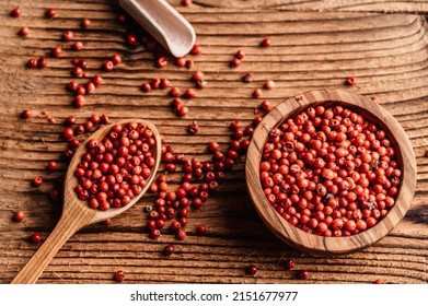 Red pepper corns in wood bowl on wooden table i. Pink peppercorns seeds. Brazil Pepper