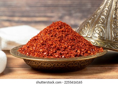 Red pepper flakes. Crushed chili pepper in bowl, dried chili flakes on wooden background. Close up - Powered by Shutterstock