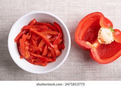 Red pepper salad, pickled red bell pepper strips in a white bowl on linen fabric. Paprika salad, made of sliced, sweet peppers, pasteurized and preserved in vinegar brine. Used as barbecue side dish. - Powered by Shutterstock