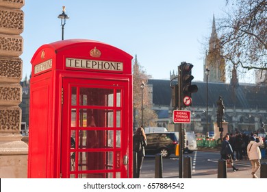 A Red Phone Booth On Blurred Crowd People Background.