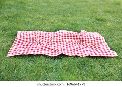 Red picnic blanket on green grass background,empty space gingham tablecloth outdoors food advertisement design.Easter decorative backdrop. - Shutterstock ID 1696641973