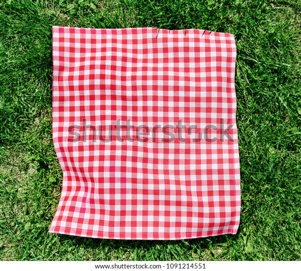 Red picnic cloth on grass\
top view.