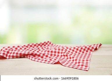 Red picnic cloth towel on wooden table natural blurred background,product display,food advertisement design.Gingham napkin.