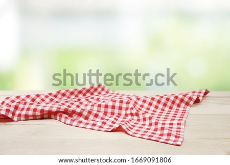 Red picnic cloth towel on wooden table natural blurred background,product display,food advertisement design.Gingham napkin.