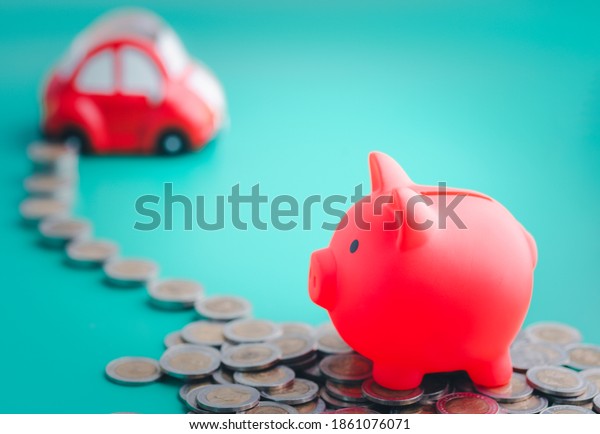 The red\
piggy bank is placed on top of a pile of coins and coins that line\
the way to the car. Money-saving\
concept