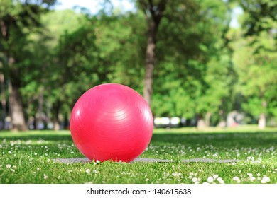 Red Pilates Ball On A Green Grass In A Park