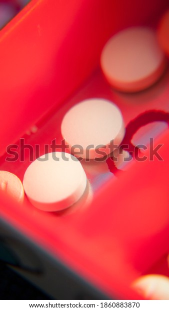 Red\
pill box compartments filled with different\
pills
