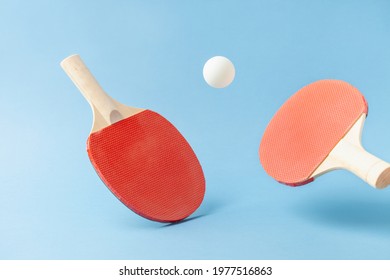 Red  ping pong table tennis paddle rackets with ball on blue background. Summer sport activity concept. Flying