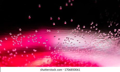 Red And Pink Abstract Air Bubbles Floating Underwater. Pockets Of Oxygen Close Up And Surface Tension On Glass Macro Background