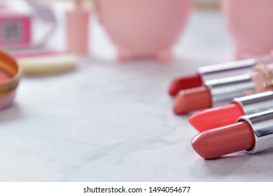 Red And Pink Female Lipsticks On Marbel Desk With Other Pink Cute Beauty Products In Background And Copy Space To The Left