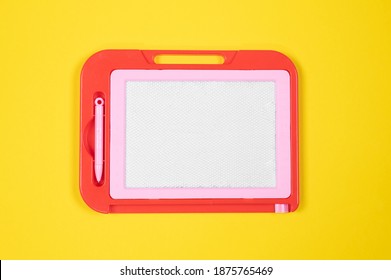 Red Pink Plastic Magnetic Drawing Board On Yellow Table. Kids Educational Toys Concept 