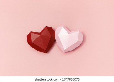 Red and pink polygonal paper hearts together on crem colored surface. Holiday background with copy space for Valentines Day. Love concept. Minimal style.
