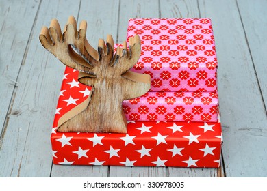 red and pink star flower pattern christmas gifts with wooden reindeer on a wooden shelves background