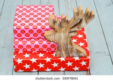 red and pink star flower pattern christmas gifts with wooden reindeer on a wooden shelves background