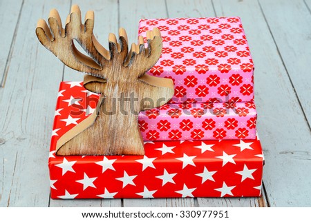 red and pink star flower pattern christmas gifts with wooden reindeer on a wooden shelves background