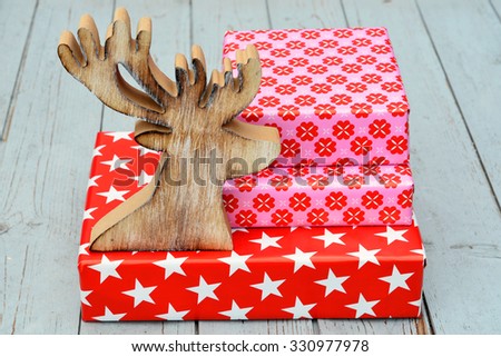 red and pink star flower pattern christmas gifts with wooden reindeer on a wooden shelves background