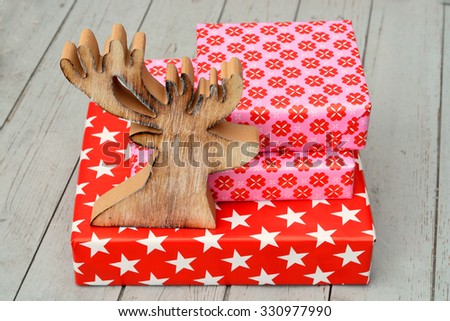 red and pink star flower pattern christmas gifts with wooden reindeer on a wooden shelves background