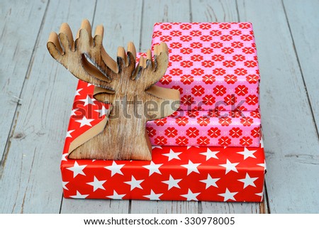 red and pink star flower pattern christmas gifts with wooden reindeer on a wooden shelves background