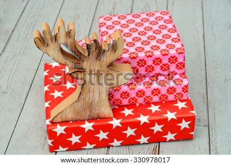 red and pink star flower pattern christmas gifts with wooden reindeer on a wooden shelves background