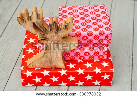 red and pink star flower pattern christmas gifts with wooden reindeer on a wooden shelves background