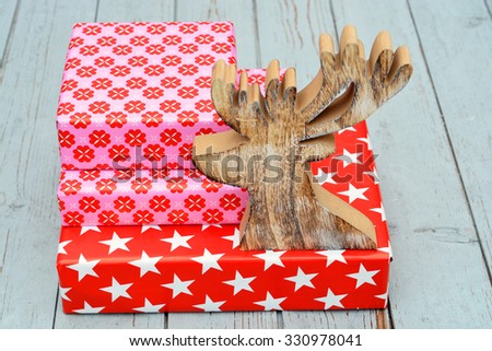 red and pink star flower pattern christmas gifts with wooden reindeer on a wooden shelves background