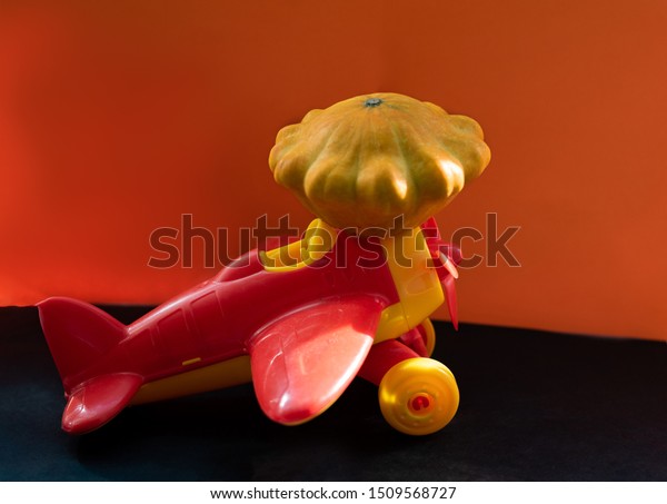 red plane carries a big pumpkin. little\
red typewriter. children\'s toy. halloween\
concept