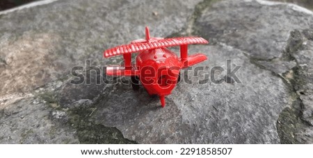 red plastic airplane children toy on flat stone