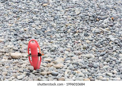 Red Plastic Buoyancy Aid In The Sand On Lonely Beach