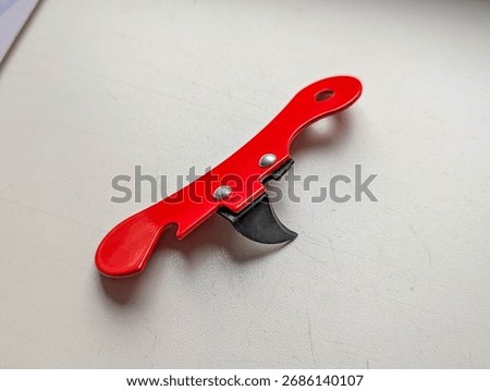Red plastic corkscrew wine bottle opener with metallic spiral lying on white surface captured from overhead flatlay perspective. High quality photograph