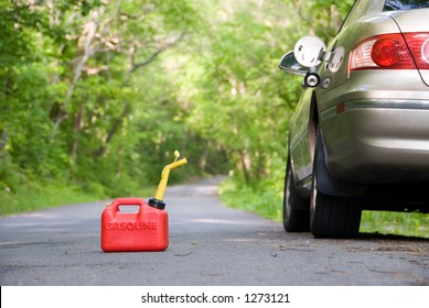 A Red Plastic Gas Can Sitting In The Middle Of A Country Road Next To A Stranded Car.