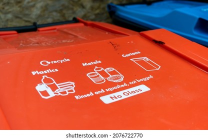 A Red Plastic And Metal Recycling Trash Can With Instructions Written On The Lid