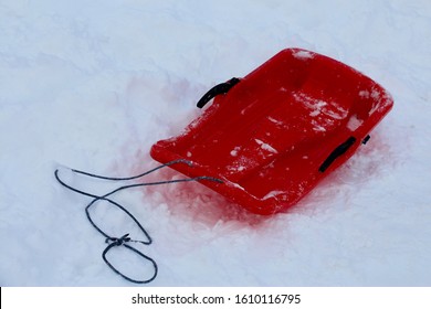 A Red Plastic Snow Sled Toboggan On The Snow In  The Mountain