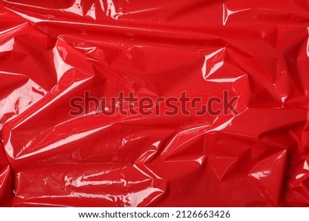Red plastic stretch wrap as background, top view
