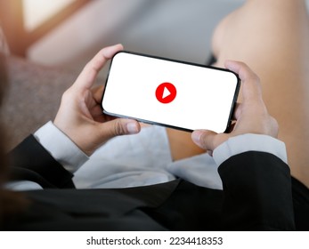 Red play button icon on white screen background on mobile smart phone, horizontal style holding by business woman's hands. Watching movie, entertainment or social network content, relaxing time. - Powered by Shutterstock