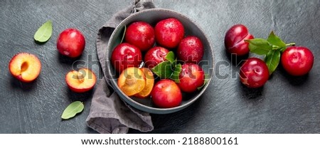 Red plums isolated on dark background. Top view. Panorama.