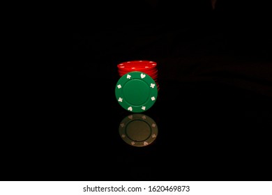 Red Pocker Chips Stack With A Green Chip In Front Isolated On Black With Reflection