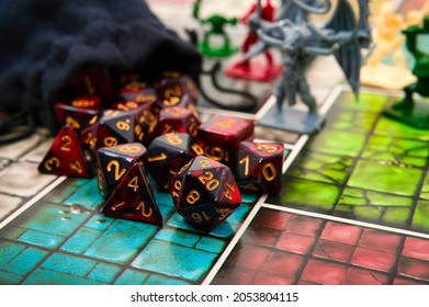 Red Polyhedral Dice Spilling Out of Black Bag with Figurines in the Background. Shallow Depth of Field.