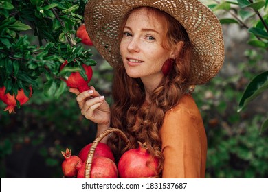 Red pomegranate garden with a happy redhead girl in a hat in an orange dress 