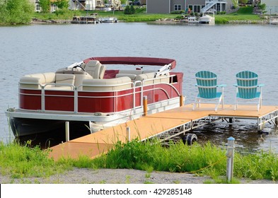 Red Pontoon Boat Tied to a Dock With Two Chairs