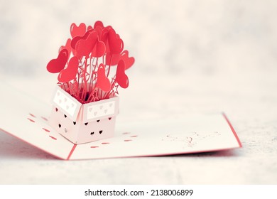 A Red Pop Up Card With Heart Shapes Bursting Out Of Box With Heart Shaped Cut Out On Box, Space For Text