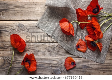 Red poppies flowers with burlap napkin on wooden table. Top view with copy space.