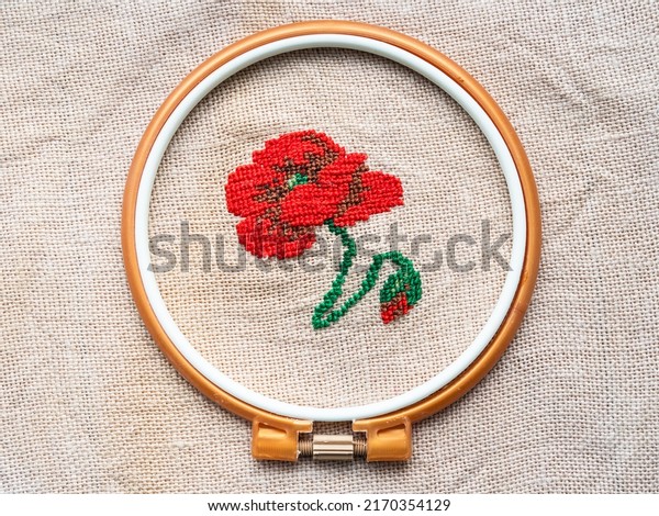 red poppy flower in plastic hoop embroidered by hand\
on fabric close up